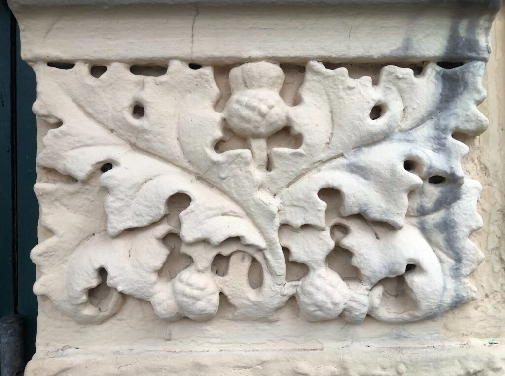 Et fasadeornament som viser et tistelmotiv.