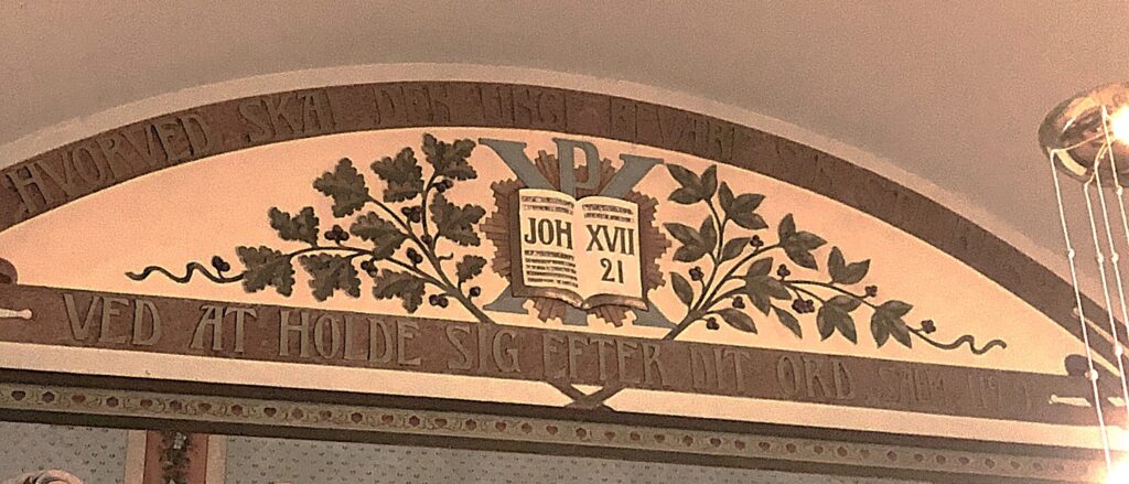 Fra dekoren i storsalen i Ynglingen/ Parkgata 14, Ålesund. KFUK/ KFUM sin gamle logo omkranset av bladdekor og bibelvers. Foto: Peder Alme v/ Norsk Håndverksinstitutt 2026