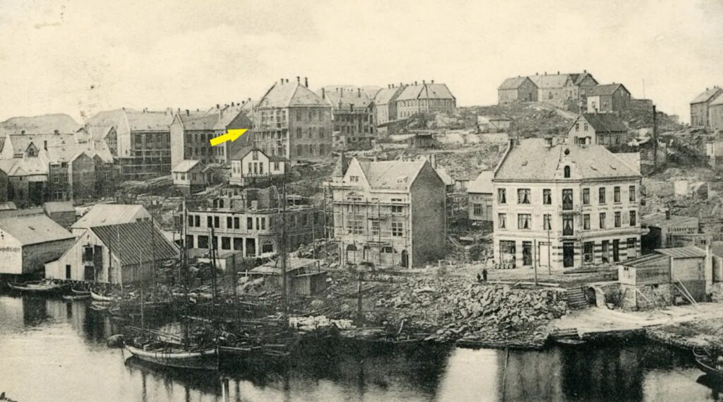 "Det nye Aalesund" reiser seg. Vi ser oppføringen av flere bygninger på Aspøya vest for Brosundet, bl.a. Øwregata 5 (gul pil). Bygningen ble tegnet av arkitekt Jens Zetlitz Monrad Kielland. Kan stukkatøren Mons Hartvedt ha svinget gipsmakerspatelen på stillasen der? Foto: Johan Nygaard, 1906/ Stiftinga Viti